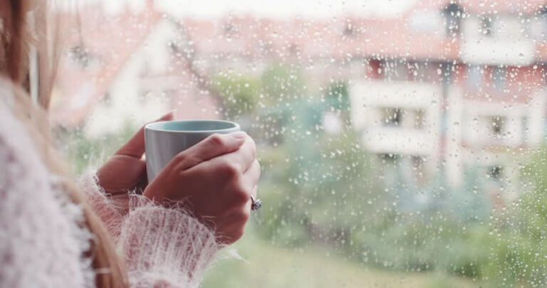 Donna ascolta il rumore della pioggia alla finestra