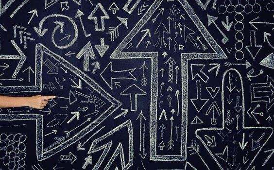 Mano che indica disegno di frecce orientate verso direzioni diverse