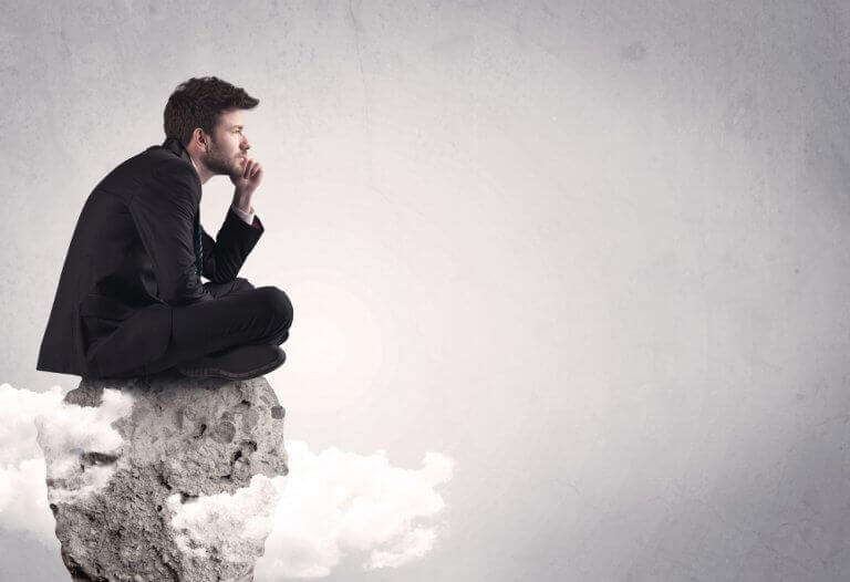 Uomo pensa seduto su una roccia