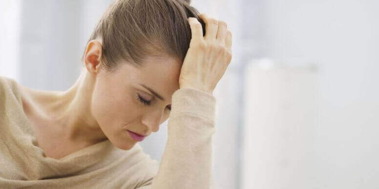 Donna con mano sulla fronte