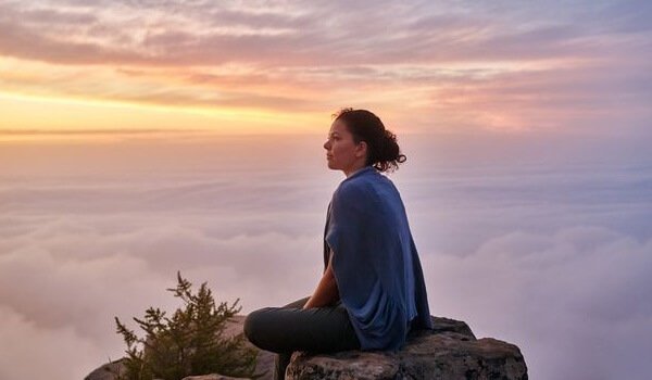 Donna tra le nuvole seduta su una roccia