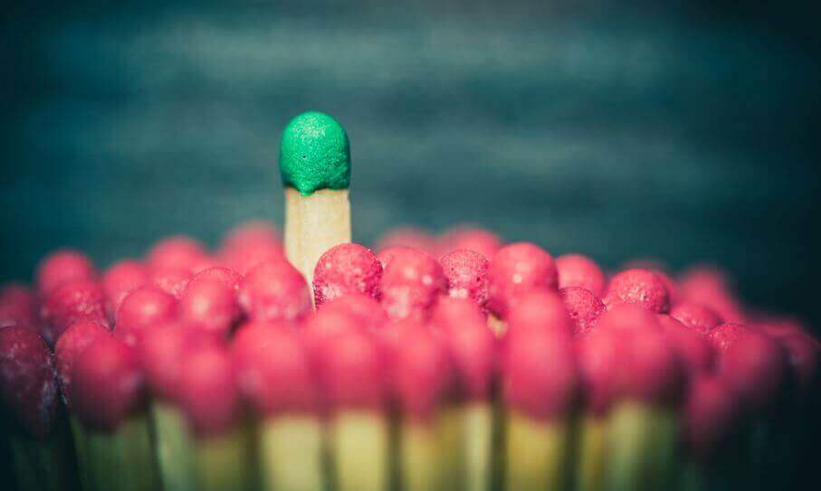 Fiammifero verde tra fiammiferi rossi