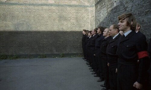 Fila di uomini con spalle al muro