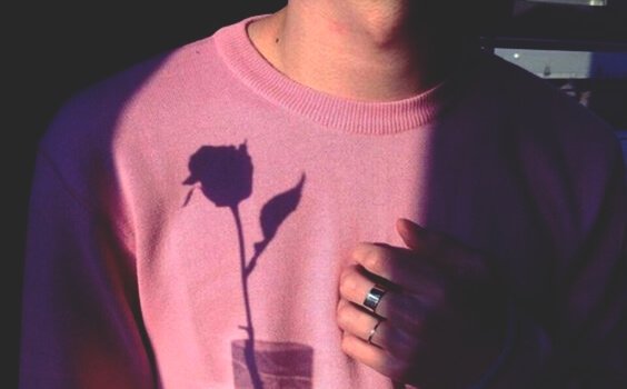 Ragazzo con la mano sul cuore e l'ombra di una rosa sulla maglia