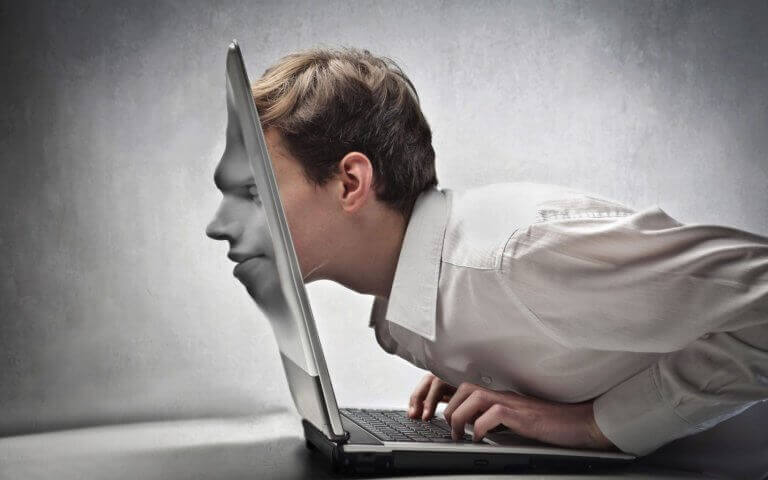 Uomo con il viso assorbito dallo schermo del portatile