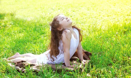 Bambina sul prato fa il saluto al sole