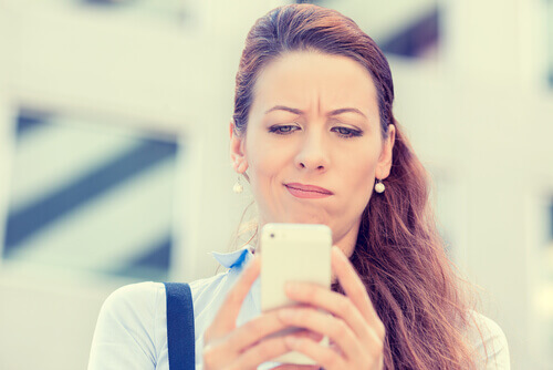 Donna che fa smorfia guardando il cellulare