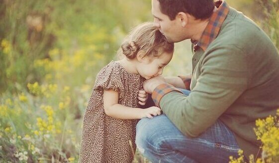 Padre che dà bacio su fronte a sua figlia