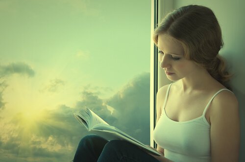 Ragazza che legge libro accanto alla finestra persone introverse