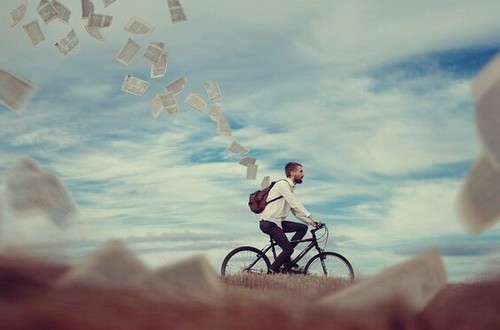 Ragazzo in bicicletta con fogli che escono dallo zaino