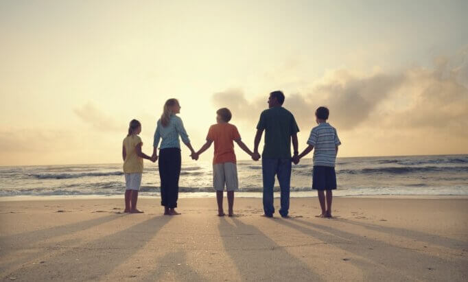 Famiglia si tiene per mano sulla spiaggia