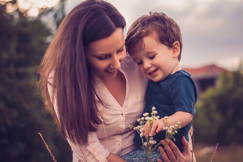 Madre con bambino in braccio che guarda un fiore