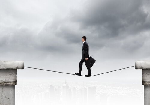 Uomo cammina su una corda sospesa a rappresentare gli atteggiamenti che non esprimono paura ma lo fanno