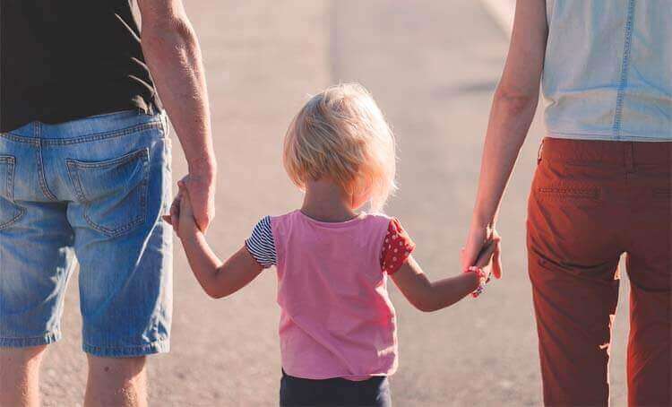 Genitori tengono per mano la figlia