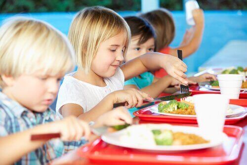 Bambini che mangiano le verdure nella mensa scolastica