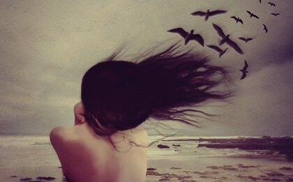 Donna in riva al mare con uccelli neri