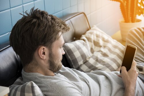 Ragazzo sdraiato sul divano con lo smartphone