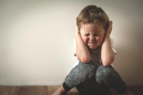 Bambino con mani sulle orecchie