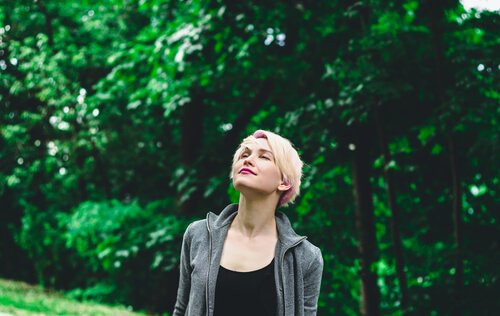 Donna con gli occhi chiusi sotto gli alberi