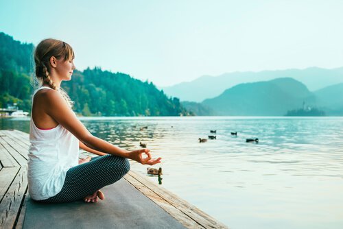 Donna seduta in meditazione davanti a un lago