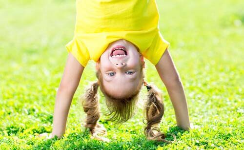 Bambina che fa la verticale sull'erba