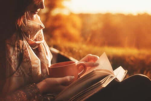 Una donna legge un libro e tiene una tazza