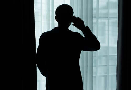 Uomo parla al telefono davanti alla finestra allo altro capo