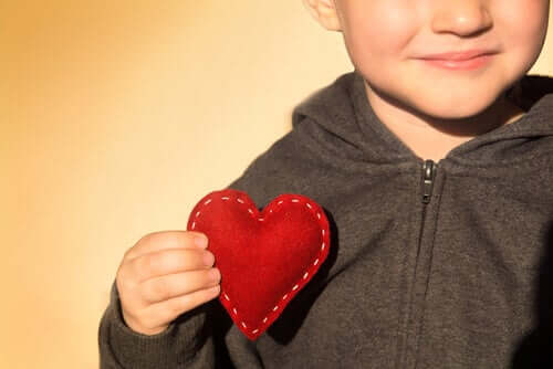 Bambino con cuore di stoffa in mano come simbolo dello sviluppo emotivo dei bambini