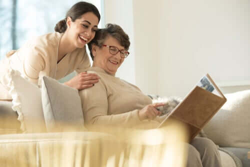 Infermiera con donna anziana che guardano un album fotografico 