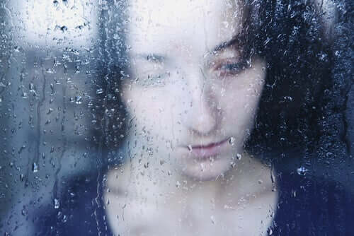 Donna triste dietro una finestra bagnata dalla pioggia