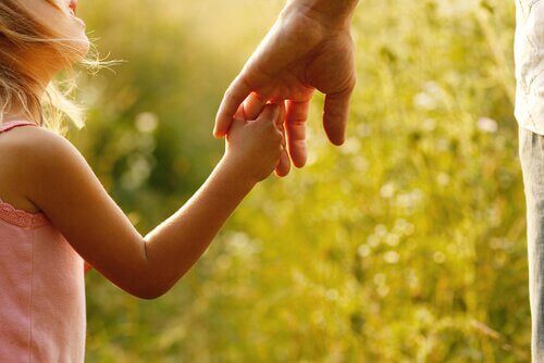 Bambina che stringe la mano di sua madre