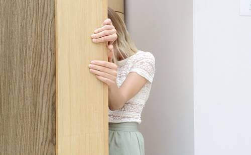 Ragazza che si nasconde dietro un muro