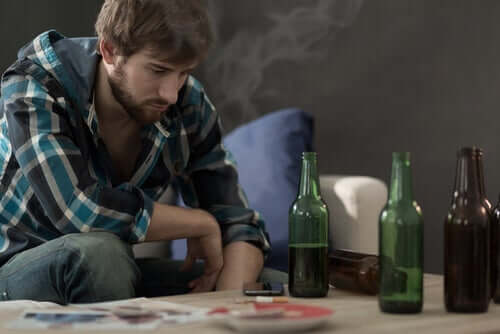 Ragazzo con bottiglie di vino sul tavolo che segue un trattamento della dipendenza da alcool