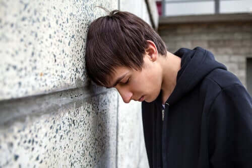 Adolescente triste con la testa appoggiata al muro