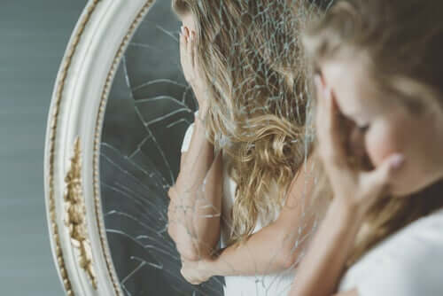 Donna angosciata davanti a specchio rotto