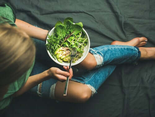 Giovane donna che mangia delle verdure