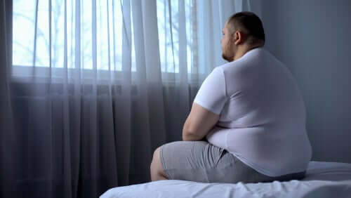 Uomo obeso seduto sul letto