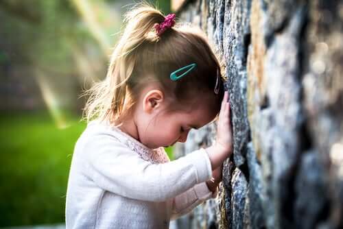 Bambina triste appoggiata a un muro