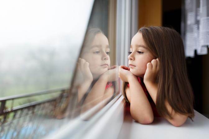 Bambina che guarda fuori dalla finestra