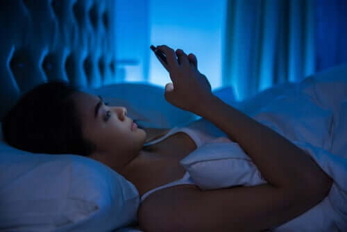 Donna che usa cellulare a letto
