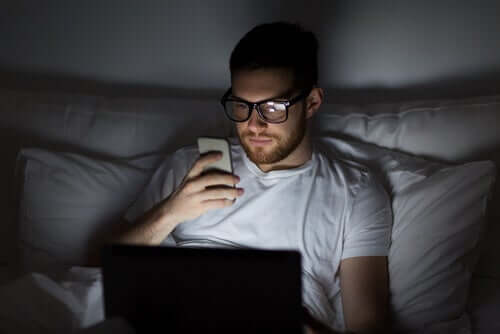 Uomo che usa il cellulare a letto