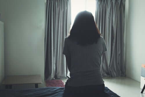 Donna che pensa seduta di spalle sul letto