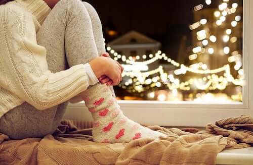 Ragazza che guarda dalla finestra le luci di natale.