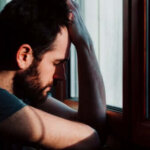 Uomo afflitto davanti alla finestra