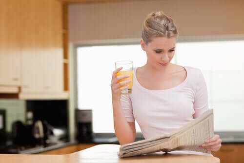 Donna con giornale e succo d'arancia