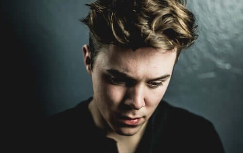 Ragazzo con la testa abbassata e sguardo triste