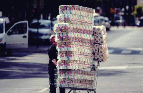 Uomo con il carrello pieno di carta igienica