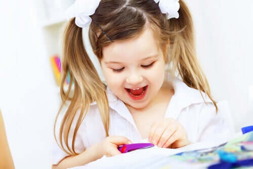 Bambina che si diverte mentre ritaglia un cartoncino