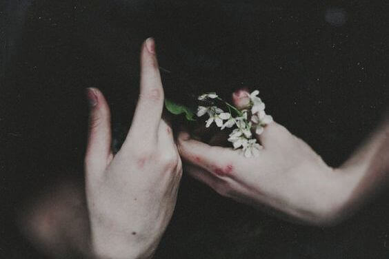 Autolesionismo emotivo e mani che stringono un mazzo di fiori