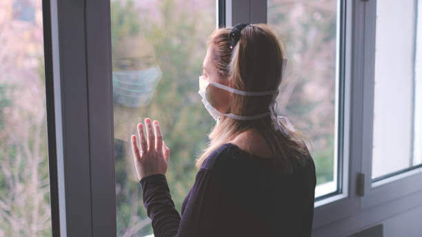 Donna con la mascherina alla finestra